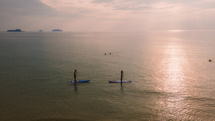 A couple of men and women paddling at a sup board in Koh Chang Thailand during sunset. stand-up...
