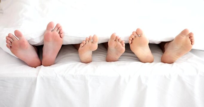 Legs of woman with two men in bed