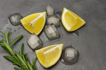 Lemon slices, rosemary sprig and melted ice on the table.