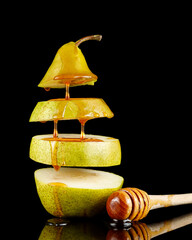 Pear with honey on black. Delicious fruit dessert. Honey flows down the pear.