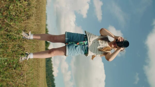 Young photographer shooting nature. Girl watching result and concentrating on process, spending leisure time outdoor on favorite hobby. Vertical shot. Phone screen view. Slow motion.