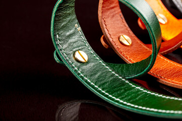 A group of multi-colored leather belts on a black background.