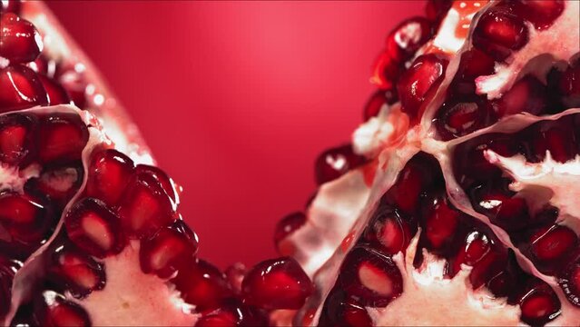 Pomegranate Splits in half and Grains rolls down with juise splash in slow motion