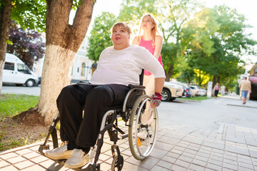 Young female caregiver pushing wheelchair with female person with disability across city street