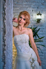 bright girl with a fashionable hairstyle in a white dress in an entourage studio