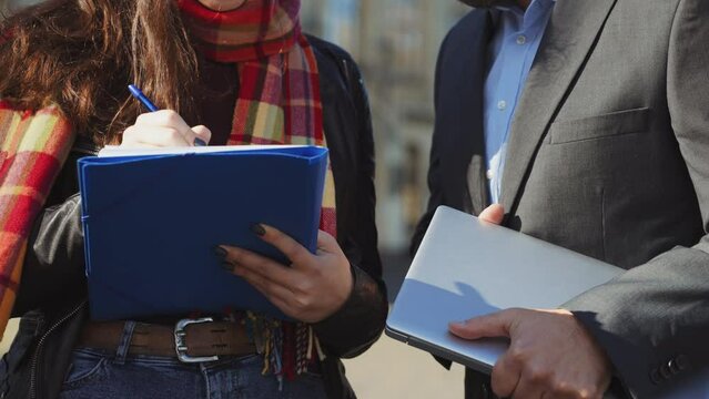 Closeup female student hends making notes and male teacher with laptop helping her. Professor tutoring student with homework or thesis. Concept of education
