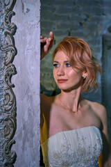 bright girl with a fashionable hairstyle in a white dress in an entourage studio