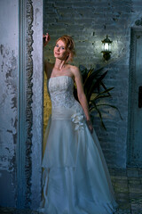 bright girl with a fashionable hairstyle in a white dress in an entourage studio