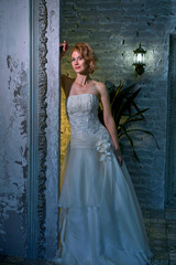bright girl with a fashionable hairstyle in a white dress in an entourage studio