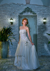 bright girl with a fashionable hairstyle in a white dress in an entourage studio