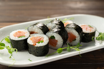 maki rolls in a row with salmon on white plate. Fresh hosomaki pieces with rice and nori. delicious japanese food with sushi roll.