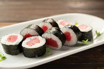 maki rolls in a row with tuna on white plate. Fresh hosomaki pieces with rice and nori. delicious japanese food with sushi roll.