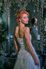 bright girl with a fashionable hairstyle in a white dress in an entourage studio