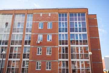 Windows of a residential multi-storey brick house. Modern buildings. The new multi-storey apartment brick building against the sky