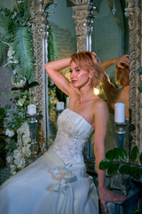 bright girl with a fashionable hairstyle in a white dress in an entourage studio
