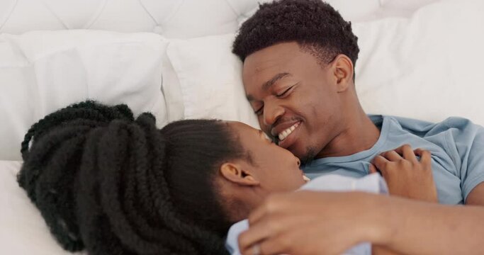 Bed, love and happy black couple romance kiss relax together on honeymoon or holiday vacation. Married African American man, woman smile and morning routine happiness relationship bonding in bedroom