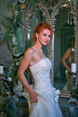 bright girl with a fashionable hairstyle in a white dress in an entourage studio