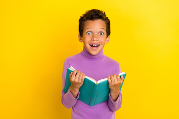 Portrait of crazy astonished person arms hold opened book unbelievable isolated on yellow color...