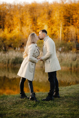Fototapeta premium Happy young couple outdoors on a sunny autumn day, couple in autumn park are kissing.