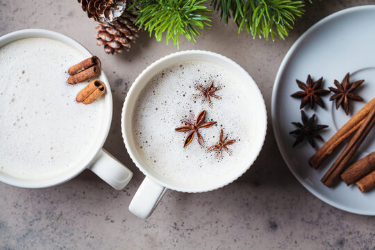 Homemade chai latte with cinnamon and star anise in white cup, dark background. Christmas background and winter drink.