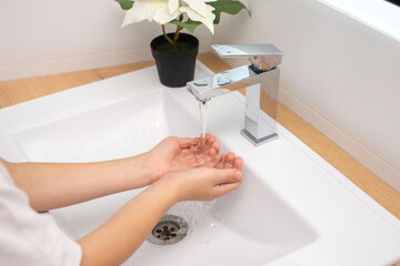 Children's hands under the water jet in the bathroom