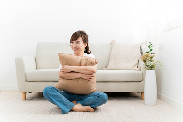 Fototapeta premium 家でクッションを持つ笑顔のアジア人女性 