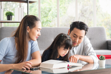 Happy family sitting together and help teaching daughter about her homework in living room.