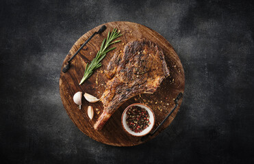 Freshly grilled Tomahawk steak on a wooden cutting board, BBQ food, top view, grey background.