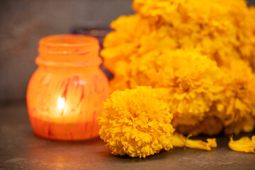 on a dark background, orange flowers - marigolds and a burning candle in an orange pot