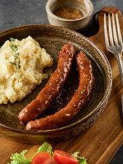 Grilled Beef bratwurst with mash potato on modern plate on wooden board.  BBQ beef sausages. German...