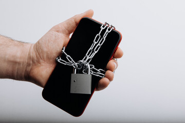 Modern smartphone with chain locked in man's hand. Social network issues and information security concept