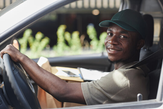 Portrait Of Young Black Man Driving Delivery Truck And Smiling At Camera Out Window