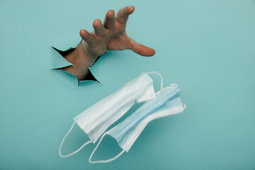 Medical mask in a male hand on a blue background with a hole, medical concept