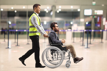 Airport worker pushing a man in a wheelchair inside the airport terminal building