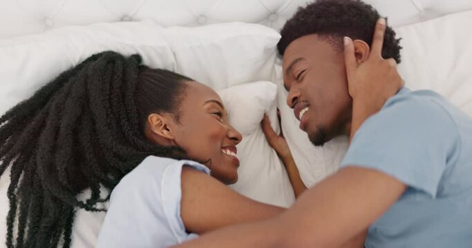 Relax, love and couple in bed in the morning, talking and smile while bonding and embracing in their home. Black woman, man and happy lovers enjoy bedroom conversation, having fun while resting