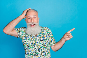 Photo of funny excited old age man bearded gray hair touch head laughing good mood finger point joke empty space isolated on blue color background
