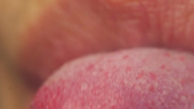 The tip of the tongue dissolves. The girl sticks out her tongue and moves it. Female mouth macro, video.