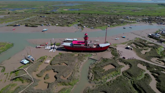 Bright red Tollesbury lightship boat moored on Essex marina marshland aerial orbiting view