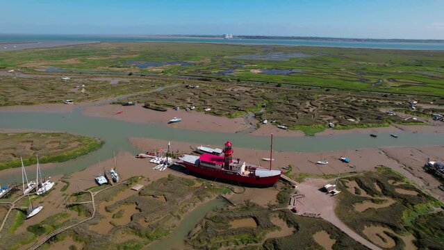 Aerial view around a light ship stuck in mud at low tide, sunny Tollesbury, UK - orbit, drone shot	
