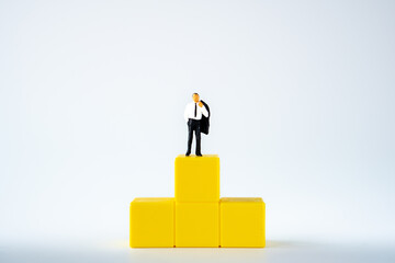 miniature businessman on winner yellow podium on white background
