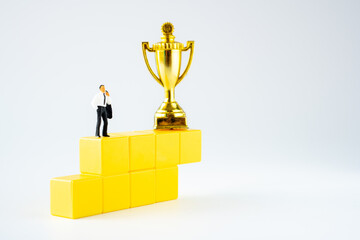 miniature businessman and Gold trophy  on winner yellow podium on white background