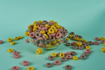 Multicolored cereal rings in a clear bowl on a blue background. 