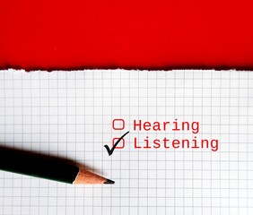 Pencil ticking on tick box with choices HEARING and LISTENING, concept of practice listening than...
