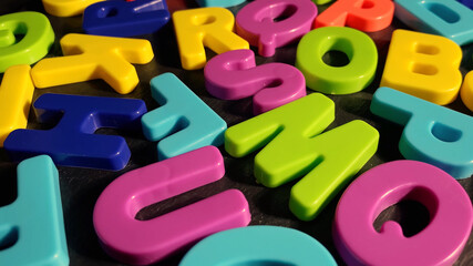 Heap of multicolored letters on black stone background. Topview. Concept back to school. Selective focus