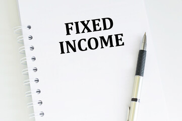 FIXED INCOME text on a notebook next to a pen on a desk, a business concept