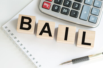 word BAIL on wooden cubes on blue background. the inscription on the cubes is reflected from the surface. business concept