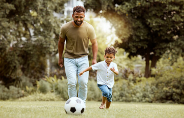 Father, child and playing with soccer ball in the park for fun quality bonding time together in...