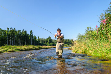 Fliegenfischer in Aktion in einer idyllischen Fluss-Landschaft an der Wertach in Schwaben