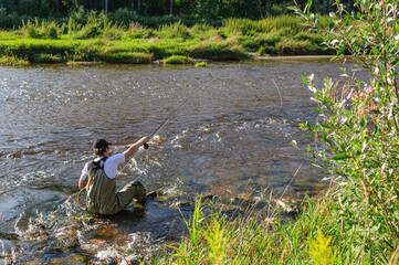 Fliegenfischer in Aktion in einer idyllischen Fluss-Landschaft an der Wertach in Schwaben