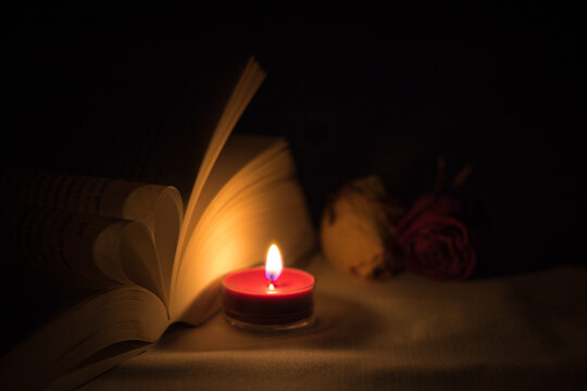 romantische Stimmung mit Teelicht vor Herz aus Buchseite und Rosen